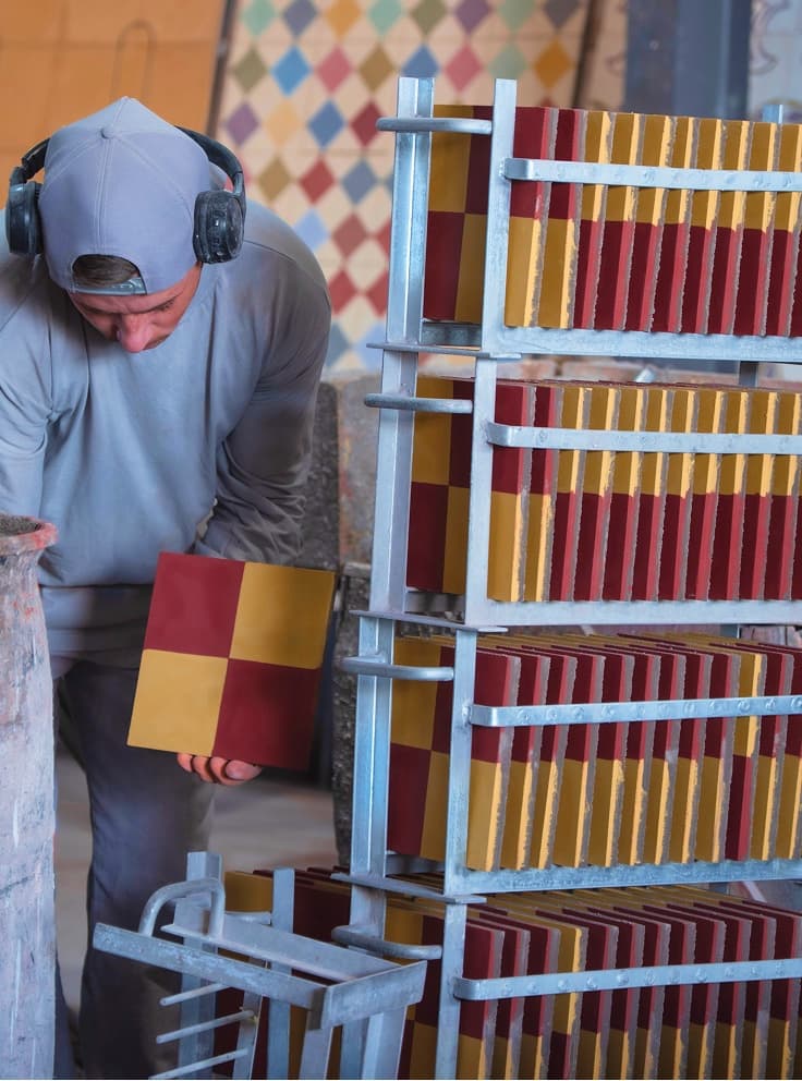 Artesão ao lado dos ladrilhos em secagem