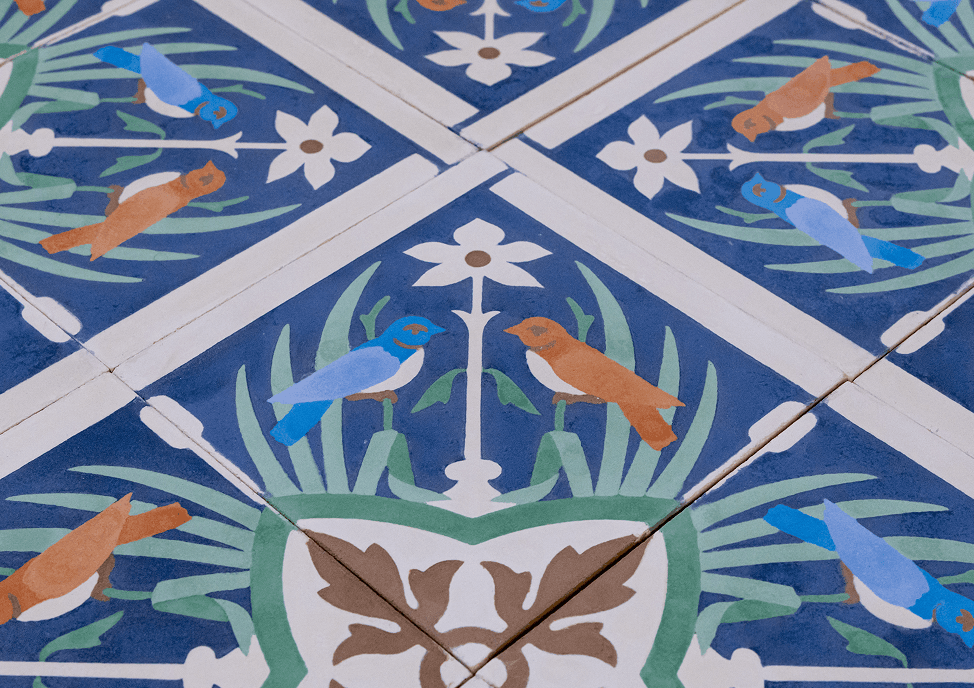 Aplicação floral com pássaros em azul e laranja