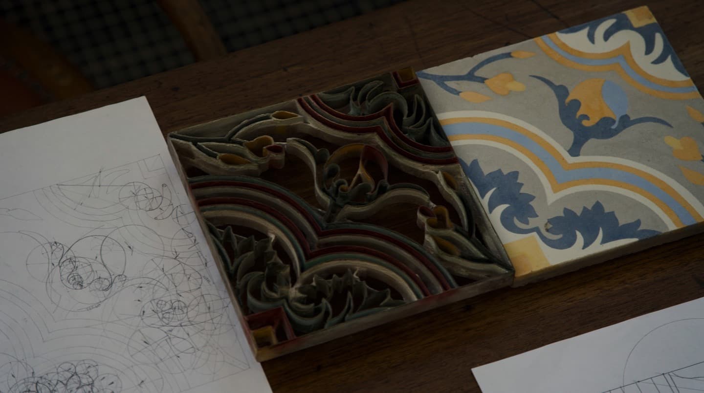 Desenhos, molde e ladrilho hidráulico sobre uma mesa de criação